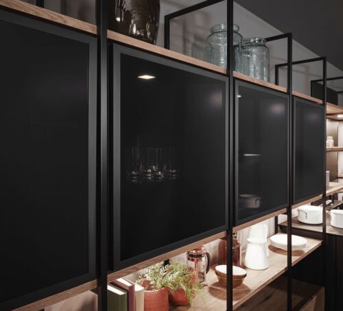 In dieser einladenden, markanten Wohnküche wurden die dunklen Vitrinen in ein Design-Regalsystem integriert. Dabei entstehen fließende und harmonische Übergänge von einem Bereich in den nächsten. Foto: AMK