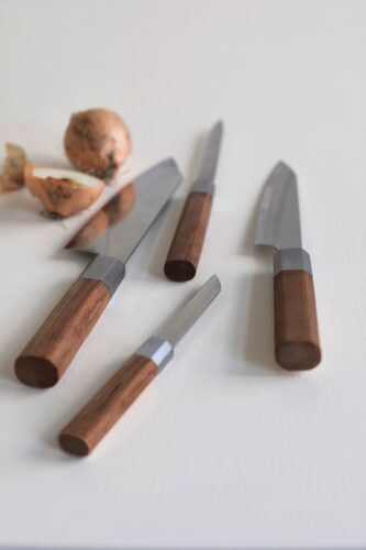Durch die Kirschholzgriffe strahlen die Messer Wärme aus. Aber es kommt vor allem auf den Komfort an und der ist bei den hochwertigen Werkzeugen mit Schichtstahlklinge gegeben. Typisch ist das große, asiatische Santoku Messer aus der Linie „Inku“ von Serax.