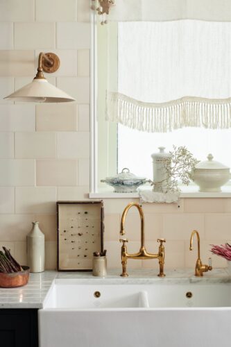 Flohmarktfunde lassen sich toll auf der Fensterbank drapieren. Ein goldfarbener, antik wirkender Wasserhahn harmoniert zum verspielten Style. Küche: „The real Shaker Kitchen“ von deVol.