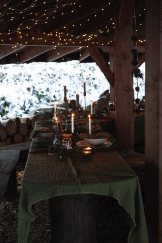 Winterliche Accessoires, wie Tannenzapfen machen sich gut auf dem gedeckten Tisch. Damit die Dunkelheit ganz romantisch erleuchtet wird, sind Lichterketten mit sehr kleinen Birnen genau richtig. Zum Tisch im Freien harmoniert robustes Keramik-Geschirr perfekt, von Ib Laursen.