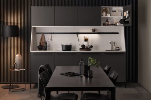Die gleichmäßige Struktur der geraden Holzstäbe erzeugt Ruhe und lockert den Look der dunklen Möbel etwas auf. Die Küche „Urban“ ist von SieMatic.