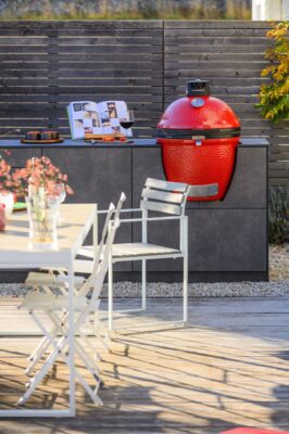 Bei den Outdoor-Küchen von Cobotha kann der Wunschgrill eingebaut werden, so auch ein Keramik-Grill. Das rote Modell ist ein echter Blickfang von Kamado Joe.  