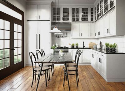 Ein eleganter Küchenboden aus warmem Holz verleiht dieser Landhausküche mit weißen Schränken und schwarzer Arbeitsplatte eine einladende Atmosphäre. Die Kombination aus rustikalem Holzboden und zeitlosem Design schafft einen harmonischen und stilvollen Raum. Foto: Getty Images