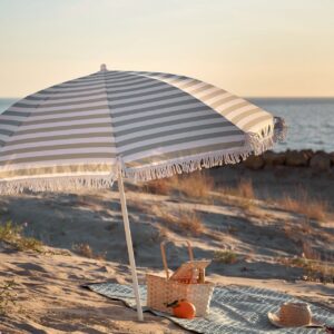 Ein Sonnenschirm ist ein Top-Schutz an heißen Tagen. Nur zu windig darf es nicht werden, damit er im Sand-Boden verankert bleibt. Er kann auch mit Schnüren und Heringen zusätzlich befestigt werden. Von Søstrene Grene.